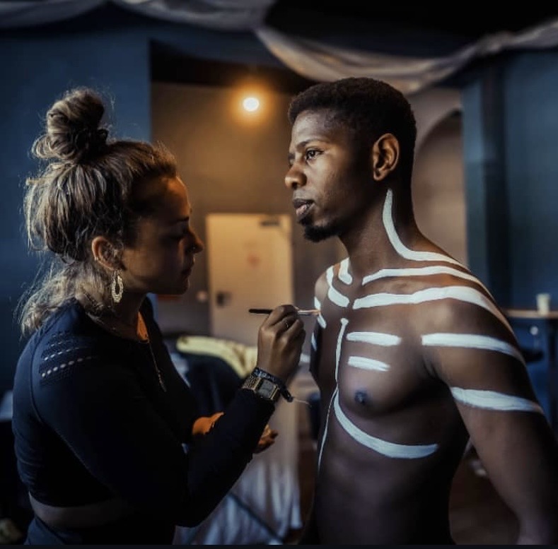 Kerstin creating bodypaint art with white tribal lines on a model